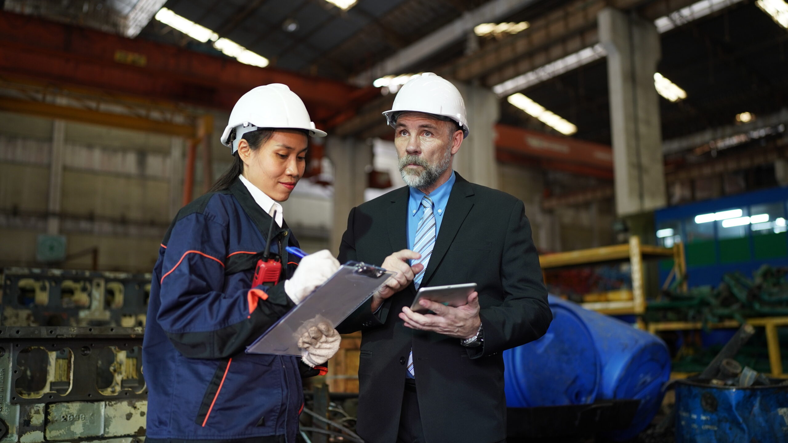 Home factory manager and female engineer in factory and inspecting factory in industry plant background.